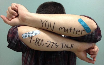 Раце на кои е напишан бројот од националната телефонска линија за превенција на самоубиства од САД